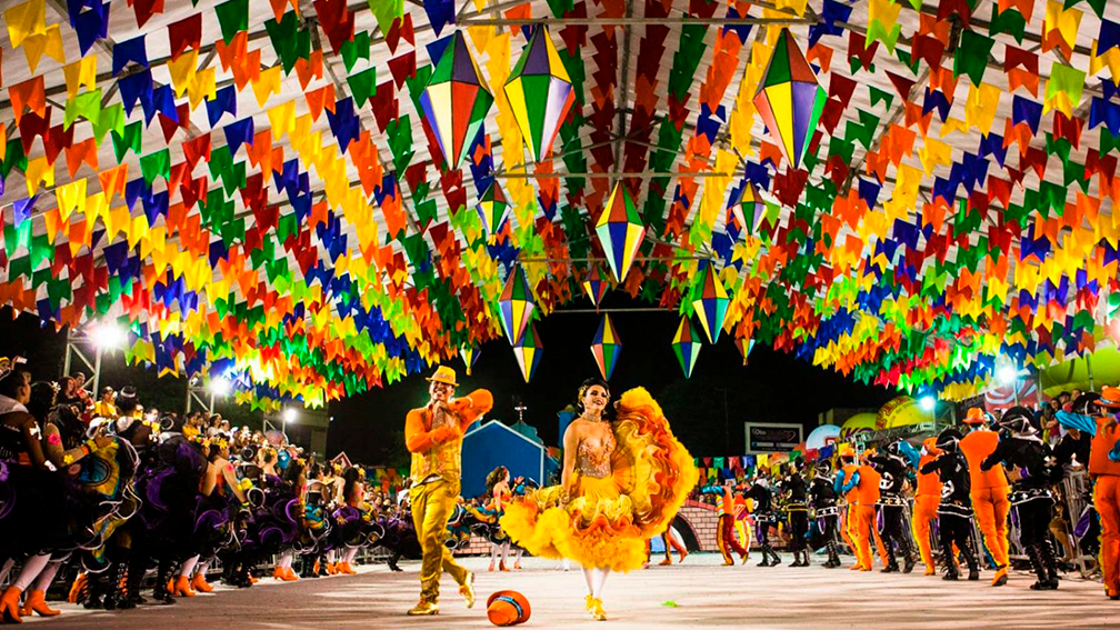 Festa noturna de São João de Caruaru, com bandeirolas e fantasias coloridas.